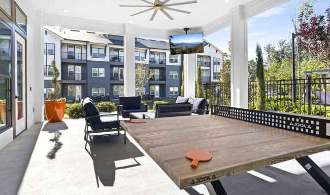 a patio with a ping pong table and chairs